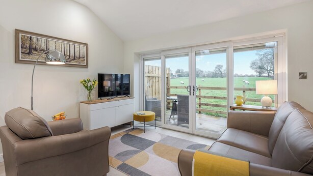 A living room with a TV, sofa, and a view of a green field. - 1 bedroom accommodation in Clitheroe (Clitheroe)