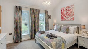 A bedroom with a bed, bedside tables, a chandelier, a large window with curtains, and a painting on the wall. - 1 bedroom accommodation in Clitheroe (Clitheroe)