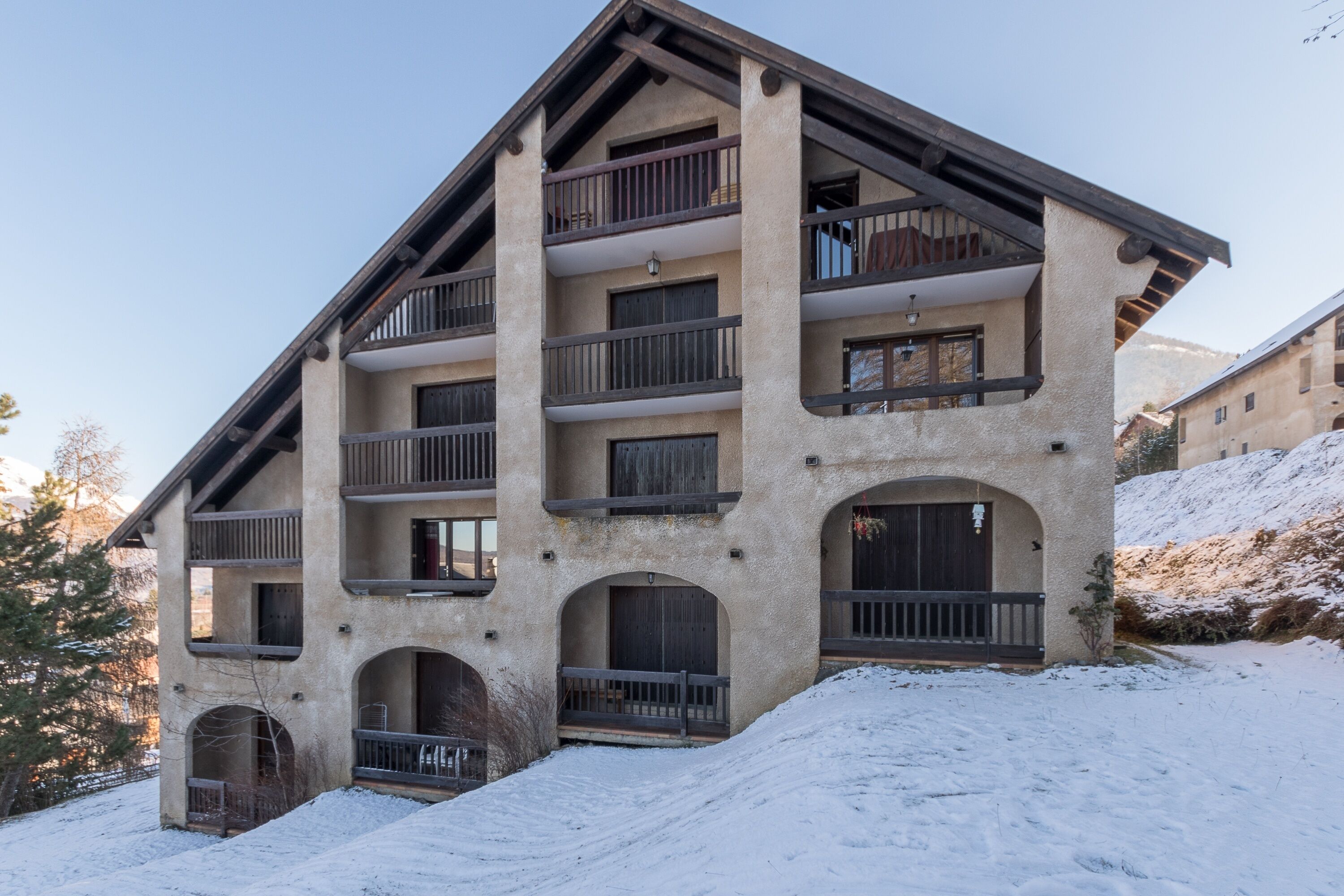A multi-story building with balconies and arched doorways, surrounded by snow.