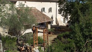 Un bâtiment de style rustique, doté d’un toit en tuiles, d’un chemin de pierre et d’une pergola en bois.