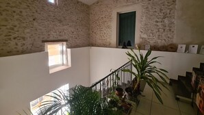 Un intérieur spacieux avec un plafond haut, un escalier et une variété de plantes en pot.