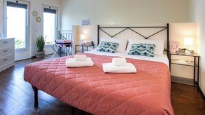 A bedroom with a large bed, two bedside tables, a dresser, and a potted plant. - Cozy loft with small pets allowed (Firenze)