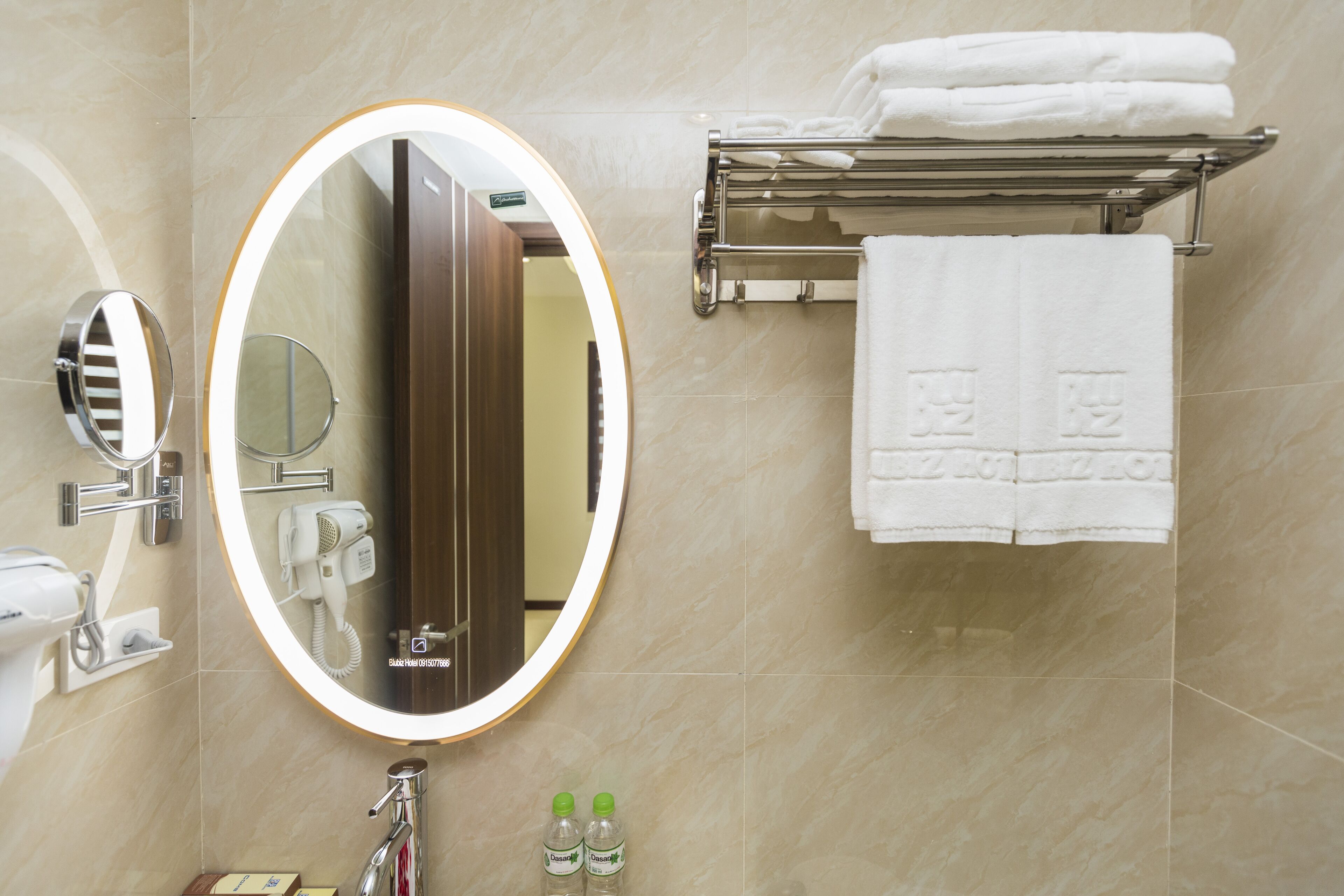 A bathroom with a large mirror, a towel rack with folded towels, and a sink with a faucet.
