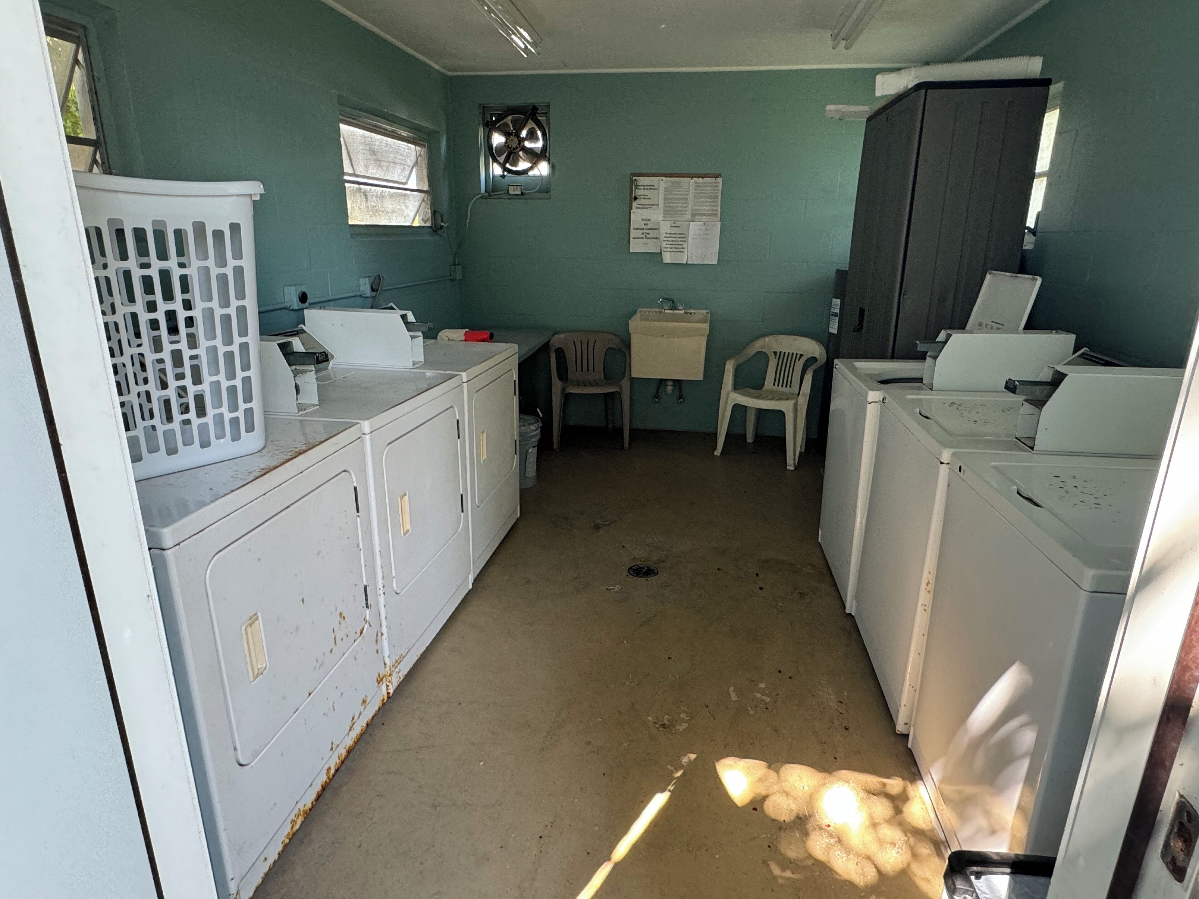 A laundry room with white appliances, a window, and a bulletin board.