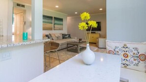 Un salon moderne avec un canapé blanc, une table basse et un vase rempli de fleurs jaunes.