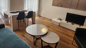 Una sala de estar moderna con comedor, televisor y un cuadro en la pared.