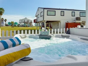 Un bain à remous avec une terrasse en bois et une clôture blanche en arrière-plan.