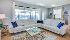 Una sala de estar moderna con un sofá modular, una mesa de centro de vidrio y amplios ventanales con vista a la ciudad.