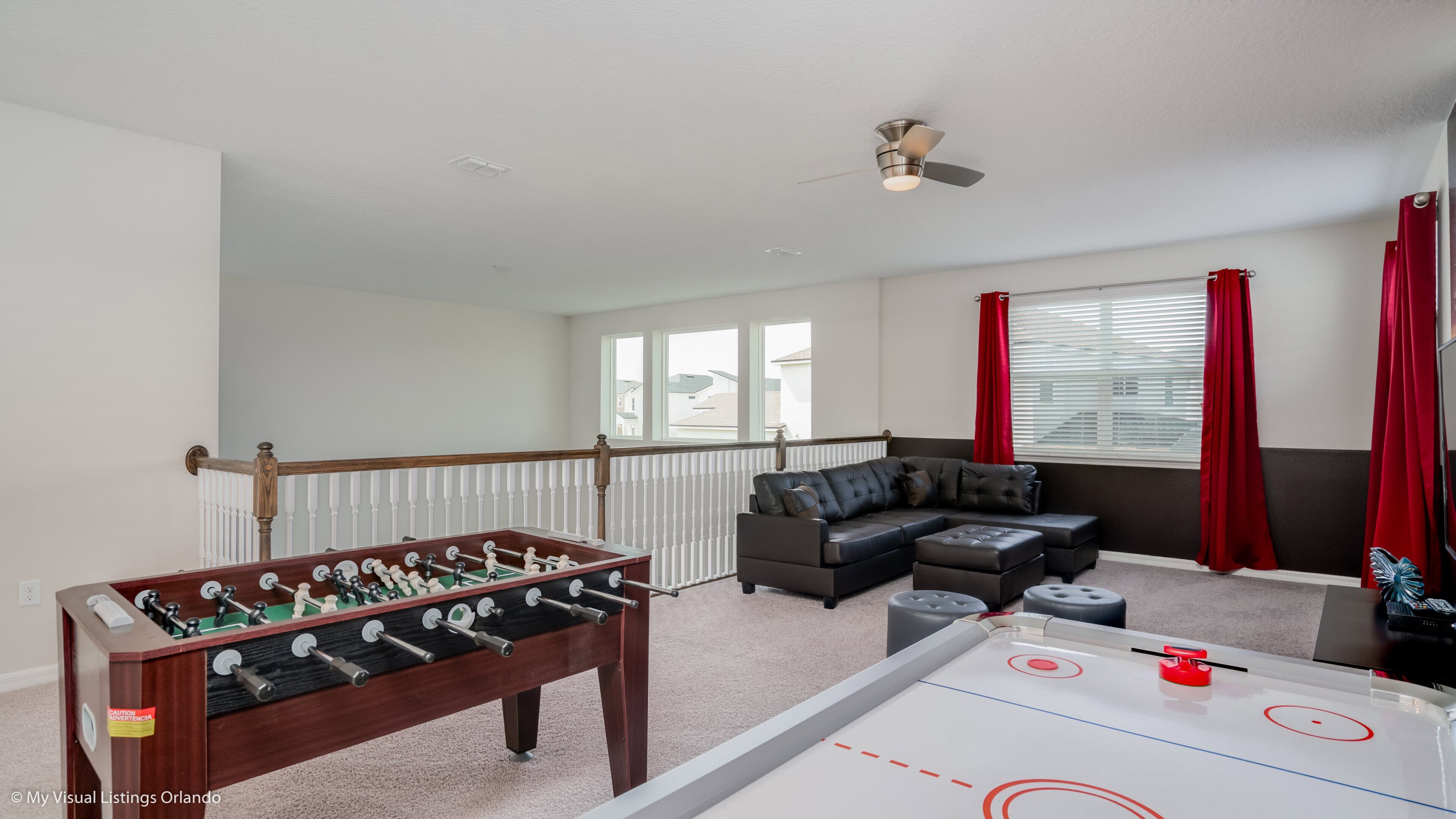 Een woonkamer met een tafelvoetbaltafel, een bank en een pooltafel.