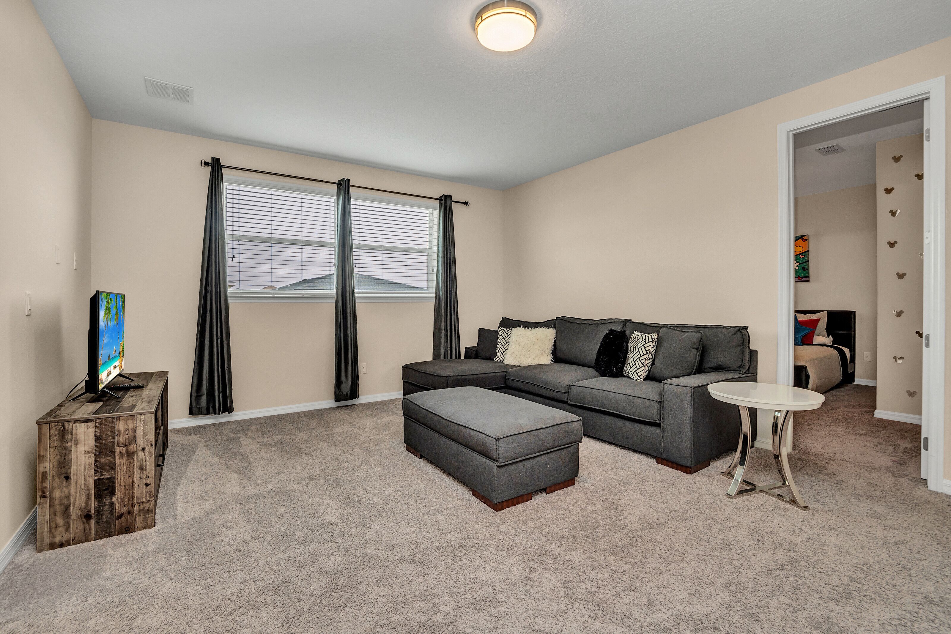 A living room with a sectional sofa, ottoman, and a small round table.