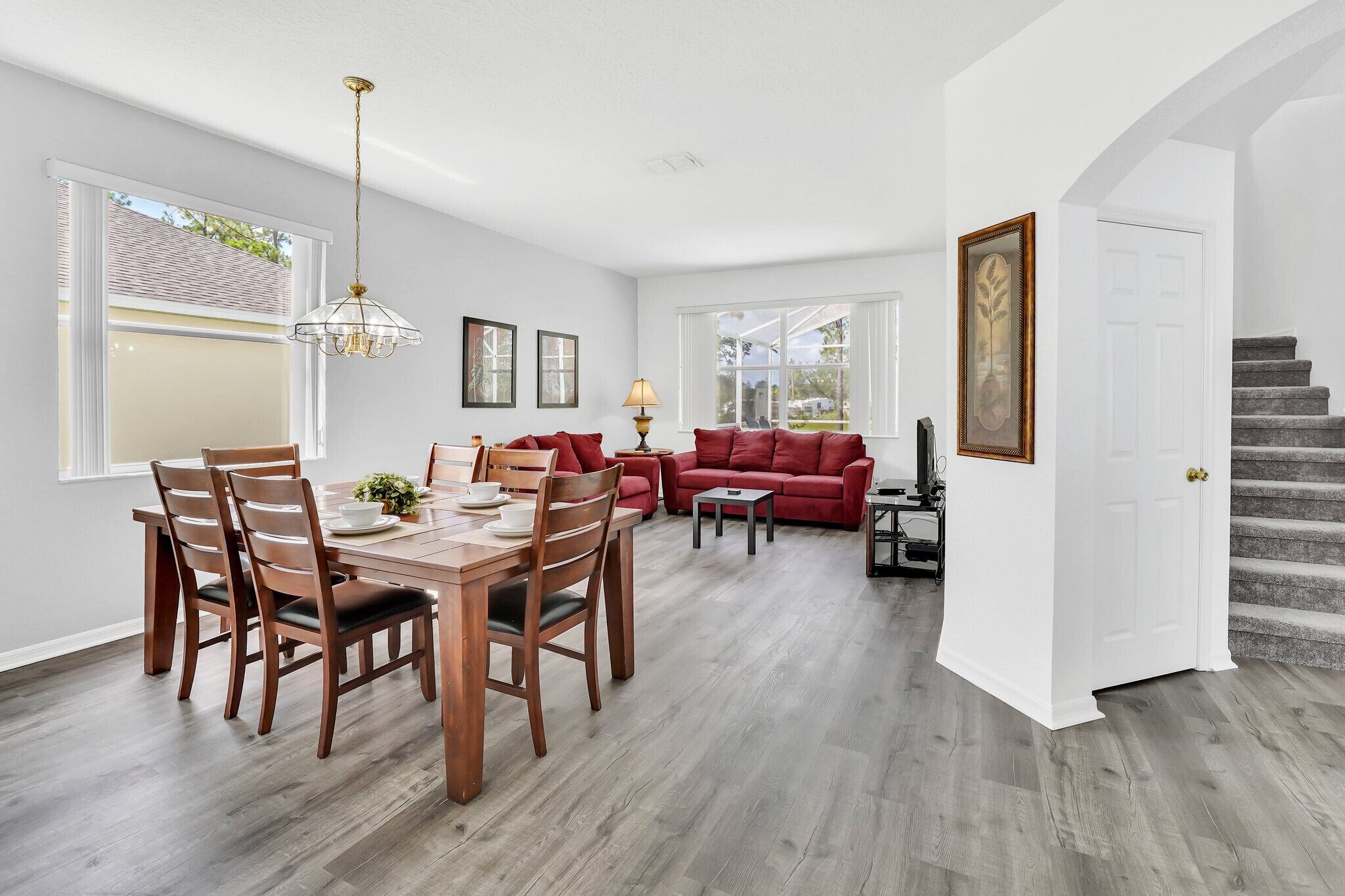 Un coin repas avec une table et des chaises en bois, un canapé rouge et une lampe.