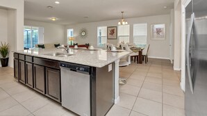 Uma cozinha moderna com ilha central, máquina de lavar louça embutida e eletrodomésticos de aço inoxidável.