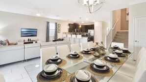 A modern dining area with a glass table set for six, surrounded by white chairs. - Last Minute Disney! Private Pool, Hot Tub, Game Room & Themed Bedrooms. Book Now! #16282 (Orlando)