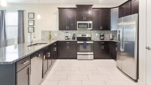 A modern kitchen with dark cabinets, stainless steel appliances, and a granite countertop. - Last Minute Disney! Private Pool, Hot Tub, Game Room & Themed Bedrooms. Book Now! #16282 (Orlando)