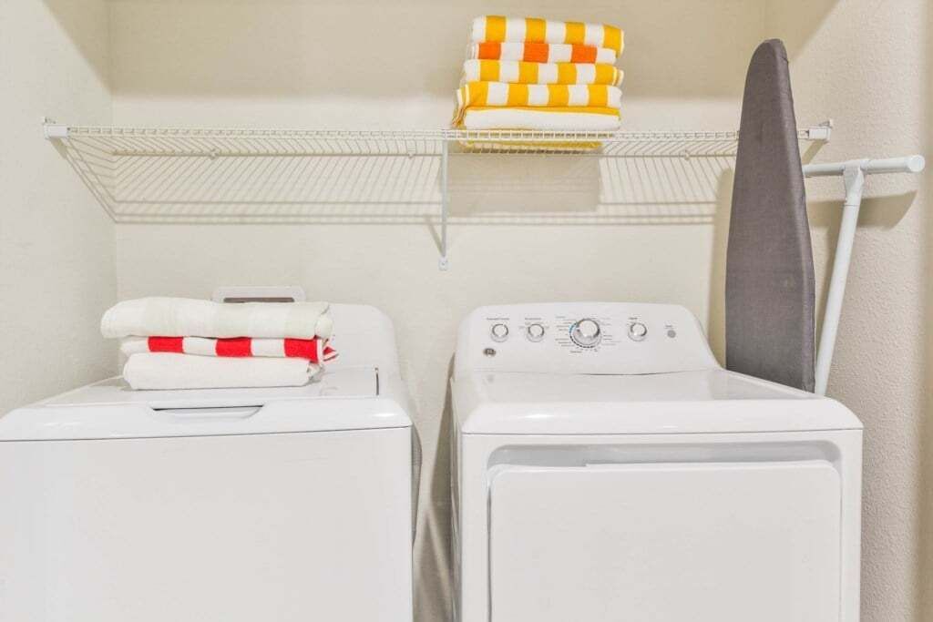 A laundry area with two washing machines and a drying rack.
