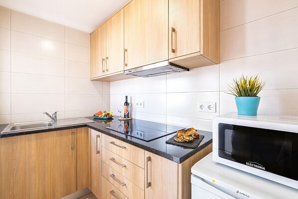 Une cuisine avec des meubles en bois, un évier en acier inoxydable, un four à micro-ondes et une plante en pot.