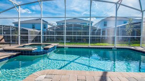 Une piscine à l’eau d’un bleu limpide, entourée d’une zone abritée d’où l’on peut admirer les maisons au loin.