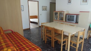 Une pièce comprenant un lit, une table à manger avec des chaises, un téléviseur et un meuble.