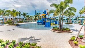 A children's play area with a slide and climbing structures, surrounded by palm trees and lounge chairs. - Last Minute Disney Getaway! Private Pool, Hot Tub & Games Room. Book Now! #16468 (Orlando)