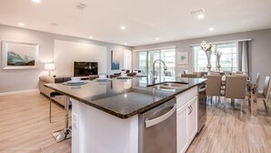 Une cuisine moderne dotée d’un îlot central, d’appareils électroménagers intégrés et d’un coin repas avec une grande fenêtre.