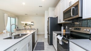 A modern kitchen with stainless steel appliances, a double sink, and a large island.