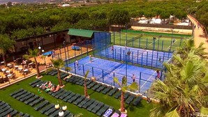 Una cancha de tenis rodeada de sillas de descanso y palmeras.