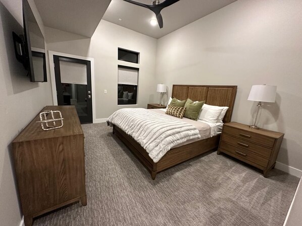 Un dormitorio con cama, mesitas de noche, cómoda y ventilador de techo.
