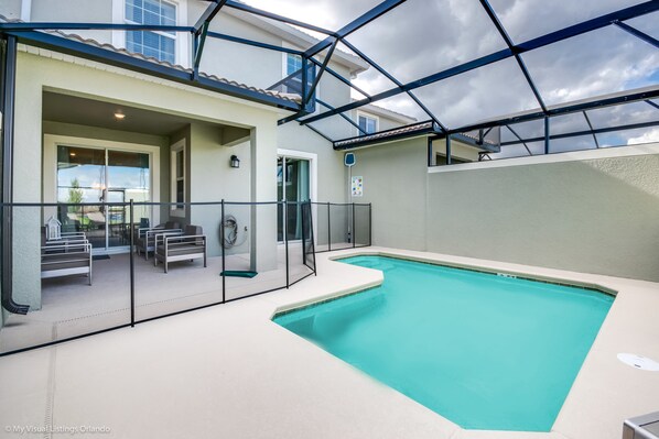 Piscina interior con cerramiento de vidrio, zona de estar y vistas al exterior.