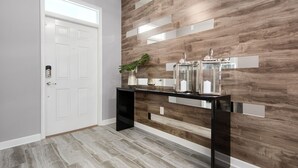 A modern hallway with a white door, a black console table, and a wooden wall with horizontal panels. - Last Minute Disney! Private Pool, Hot Tub, Game Room & Themed Bedrooms. Book Now! #21214 (Orlando)