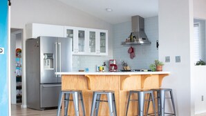 A modern kitchen with a central island, stainless steel appliances, and bar stools. - PDX Penthouse with Mountain & River Views (Portland)