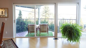 A room with a sliding glass door leading to a balcony with a wooden deck and two chairs. - PDX Penthouse with Mountain & River Views (Portland)