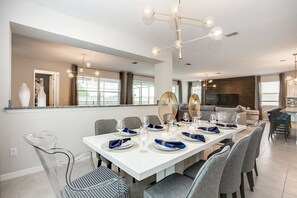 Un espace de salle à manger moderne, avec une longue table dressée pour six personnes, entourée de chaises à revêtement gris.