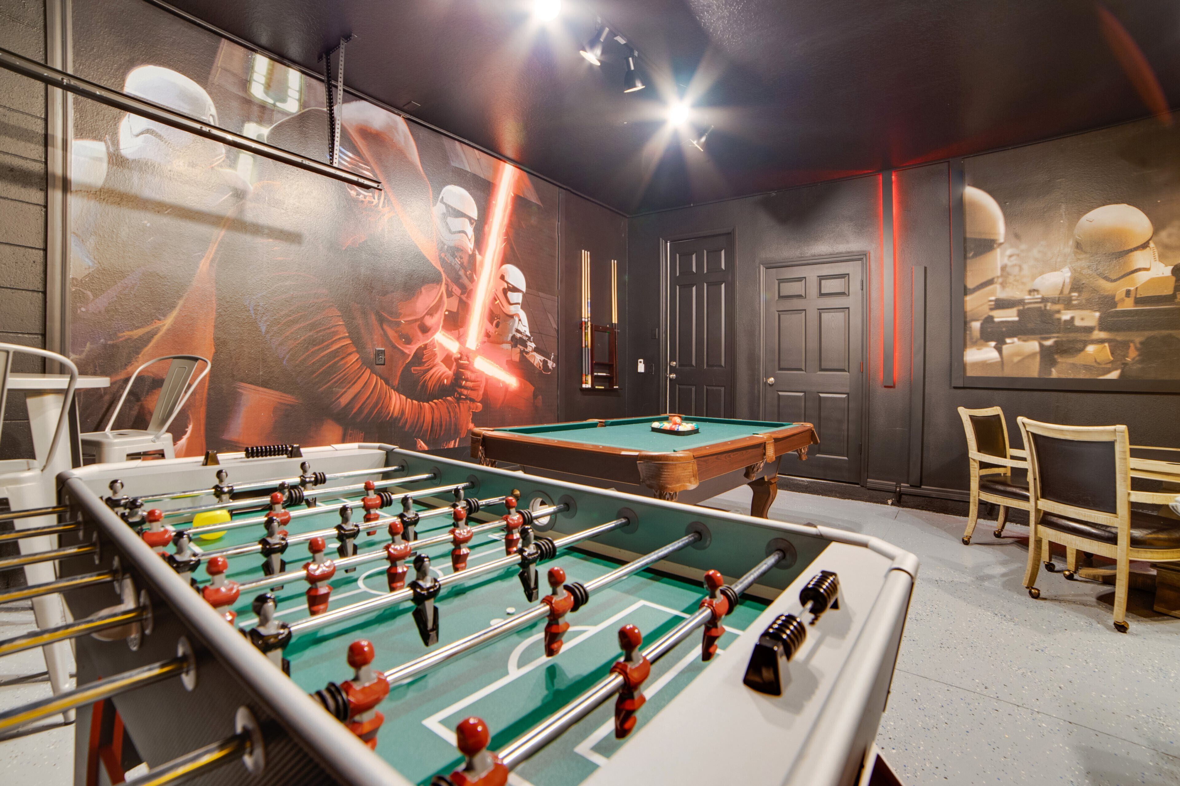 Une pièce équipée d’un baby-foot, d’une table de billard et décorée avec des œuvres d’art murales sur le thème de Star Wars.