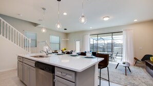 Una cocina moderna con una isla central, electrodomésticos de acero inoxidable e iluminación colgante.