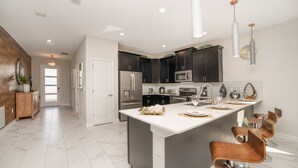 A modern kitchen with dark cabinets, stainless steel appliances, and a central island with bar stools.