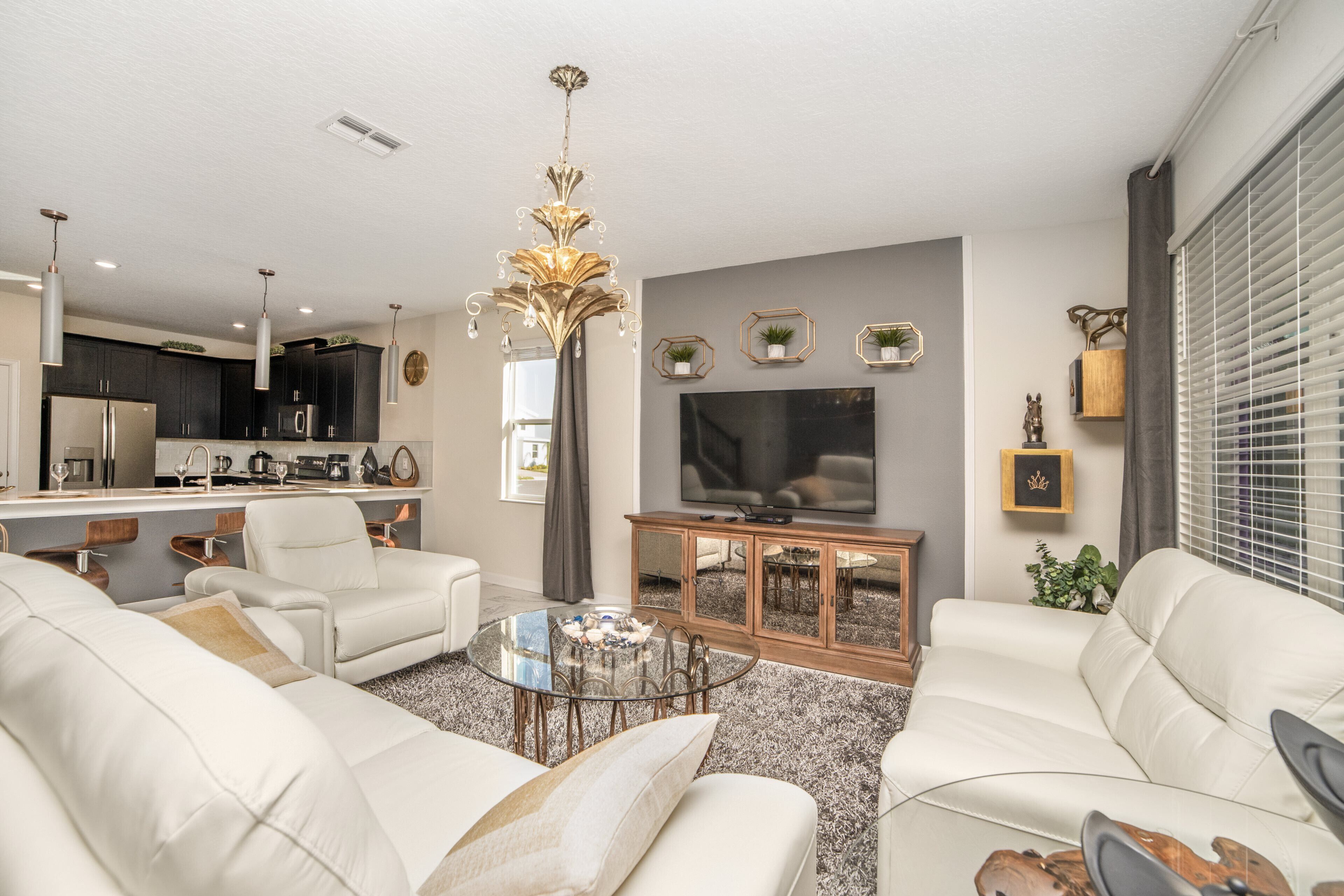 A modern living room with a sofa set, a glass coffee table, and a television.