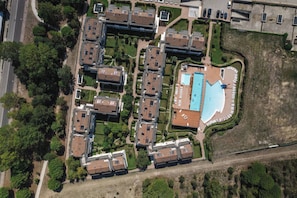 An aerial view of a residential complex with multiple apartment buildings, a swimming pool, and surrounding greenery. - Residenz Evanike Wohnung B2 1S Erdgeschoss M2 für 4 Personen (Bibione)