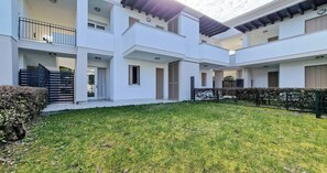 Un immeuble moderne à plusieurs étages, doté d’une cour intérieure, de balcons et d’une pelouse bien entretenue.