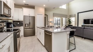 Una cocina moderna con electrodomésticos de acero inoxidable, armarios blancos y una isla central.
