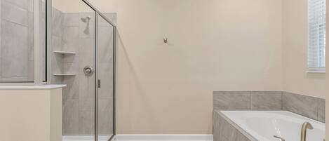 A modern bathroom with a glass-enclosed shower, a freestanding bathtub, and a vanity with a mirror.