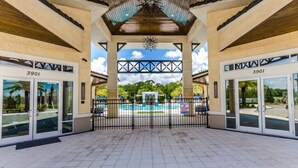 A covered entrance area with glass doors marked "3901", a pool, and a view of greenery.