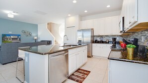 A modern kitchen with white cabinets, a stainless steel refrigerator, and a granite countertop.