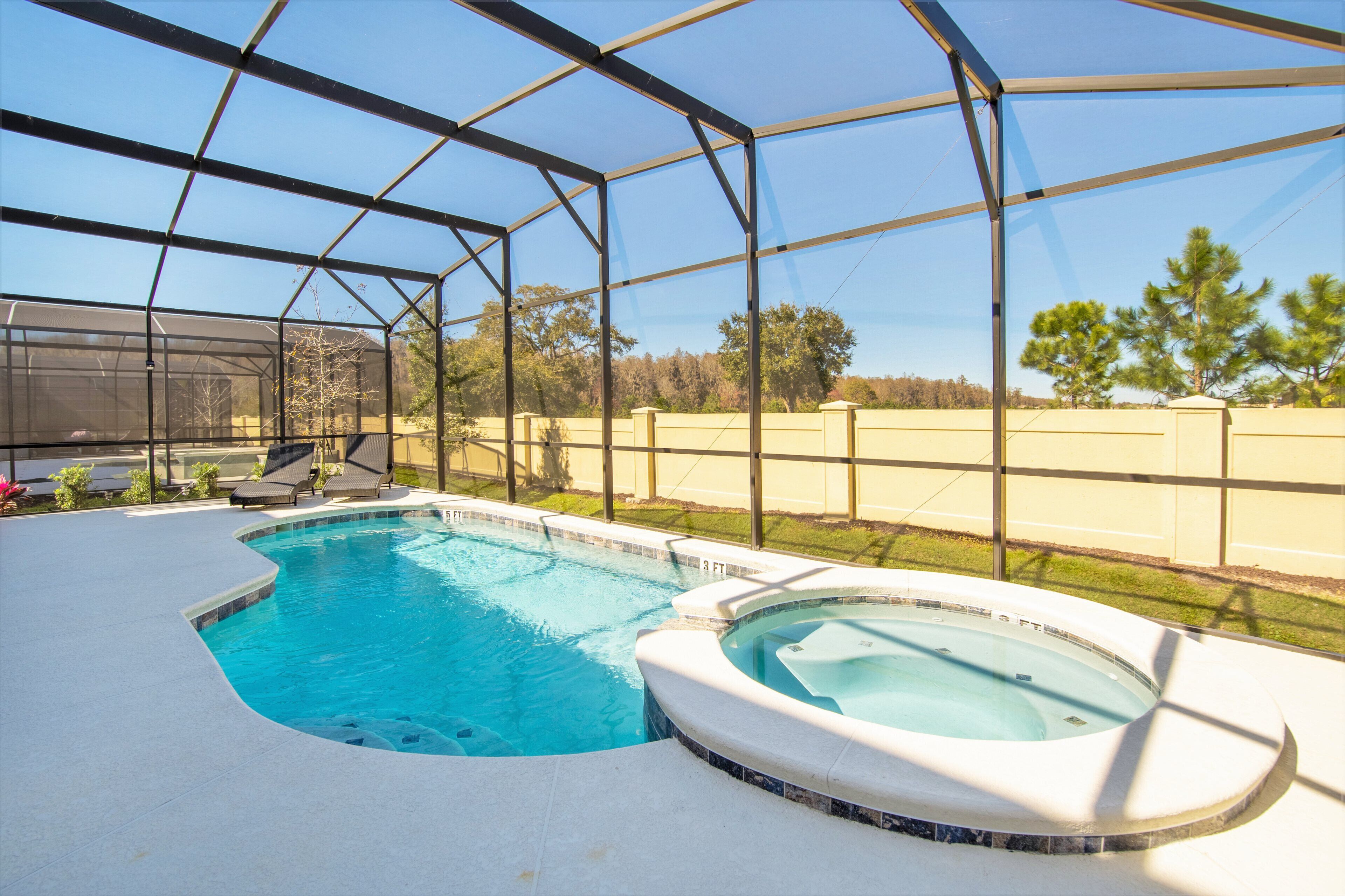 Una piscina amb un banyera d'hidromassatge, envoltada per una zona coberta amb gandules.