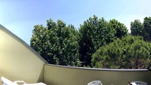 Eine Dachterrasse mit einem weißen Liegestuhl, einem Tisch mit roter Tischdecke und einer Champagnerflasche.