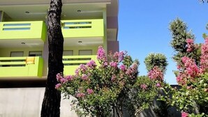 Ein mehrstöckiges Gebäude mit Balkonen und einem Baum im Vordergrund.