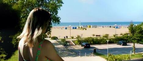A view of a beach with a parking area and a building in the foreground.