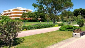 Un hôtel composé d’un immeuble à plusieurs étages, d’un chemin pavé et d’un grand arbre situé au premier plan.