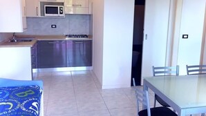A compact kitchen with white cabinets, a microwave, and a gas stove. There is a dining area with a table and chairs.