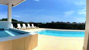 A rooftop swimming pool with lounge chairs and a clear view of the city skyline.