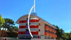 Un edificio moderno con techo curvo y una aguja blanca alta.